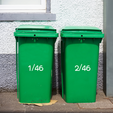 Load image into Gallery viewer, Two green recycling bins labelled "1/46" and "2/46" stand on a sidewalk against a grey pebbledash wall, suggesting organised waste management.