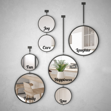 Load image into Gallery viewer, A cluster of six round mirrors with black frames on a gray wall, each reflecting home interiors. Words like Joy, Care, Laughter, Fun, Family, Happiness, and Love are inscribed on them, conveying warmth and positivity.