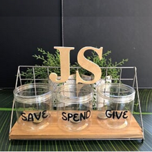 Load image into Gallery viewer, Three containers labelled "Save" and "Spend" and "Give" with a decoration of letters "JS" and artificial greenery in the